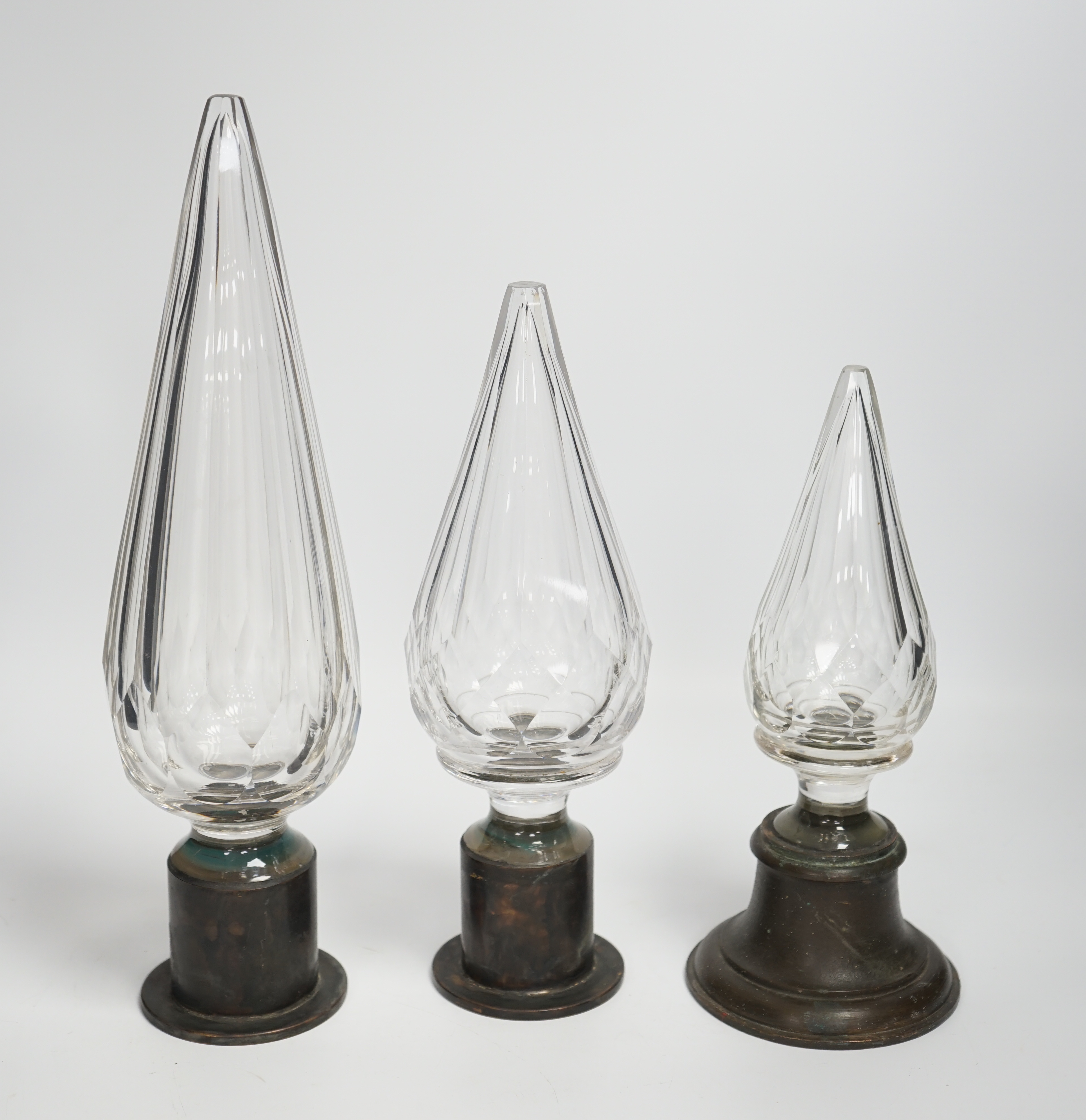 Three Large cut glass stoppers mounted on brass bases, highest 32.5cm